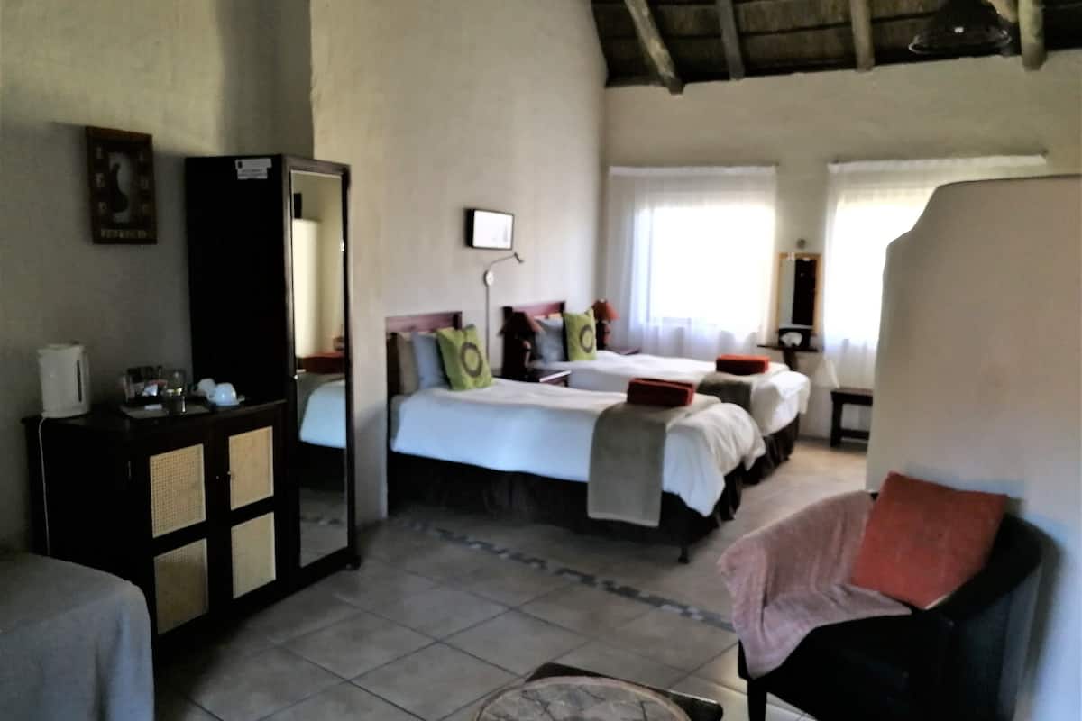 A hotel room with two beds, a large mirror, a small table, and a chair.