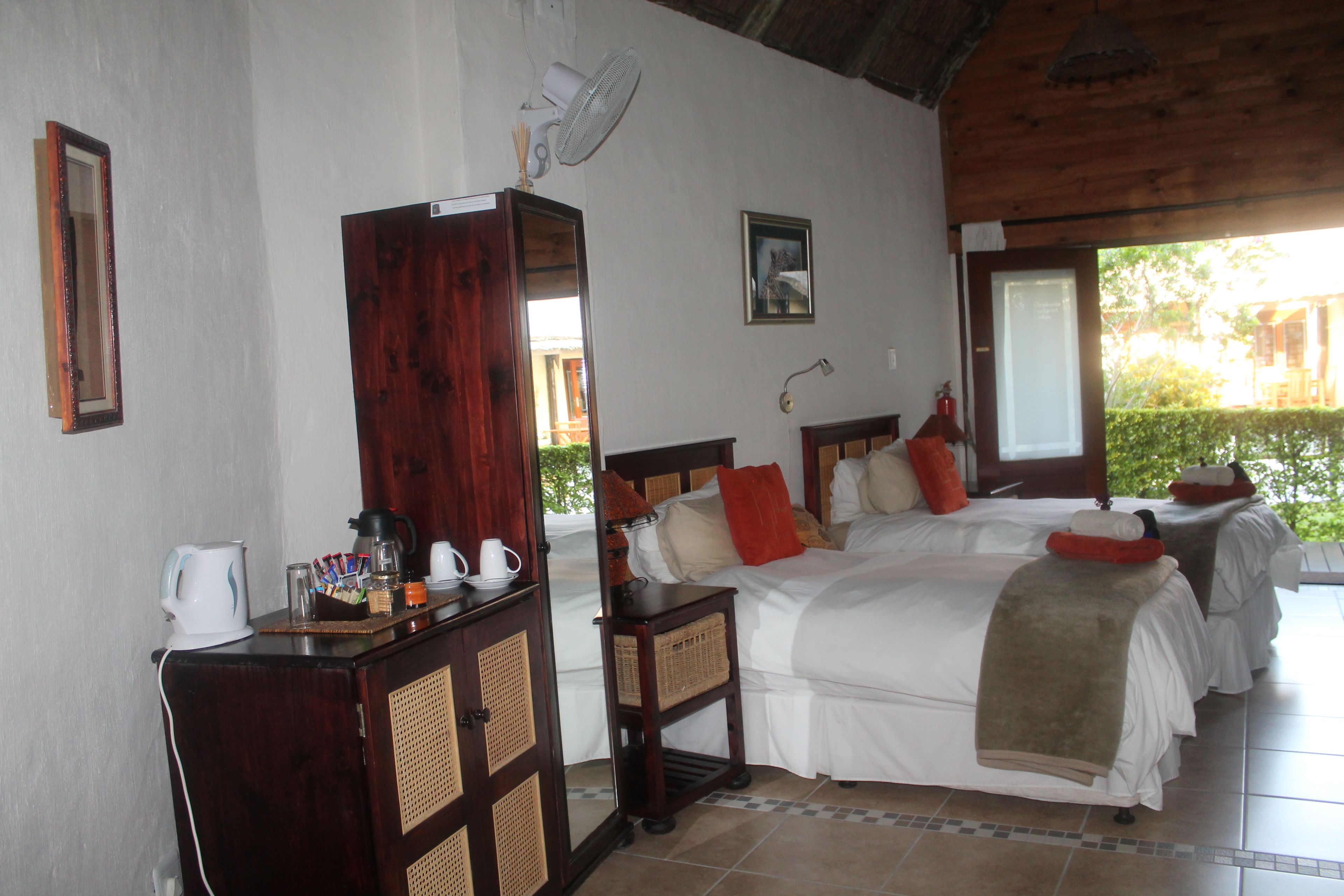 Habitación de hotel con dos camas, un aparador de madera, un ventilador y vistas al exterior.