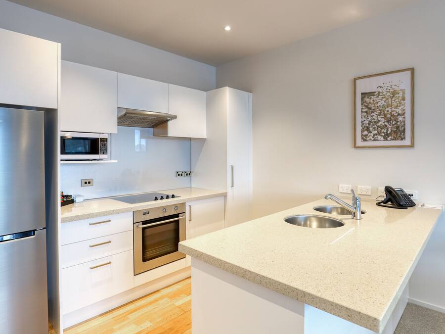 Una cocina moderna con armarios blancos, electrodomésticos de acero inoxidable, un microondas y un lavamanos.