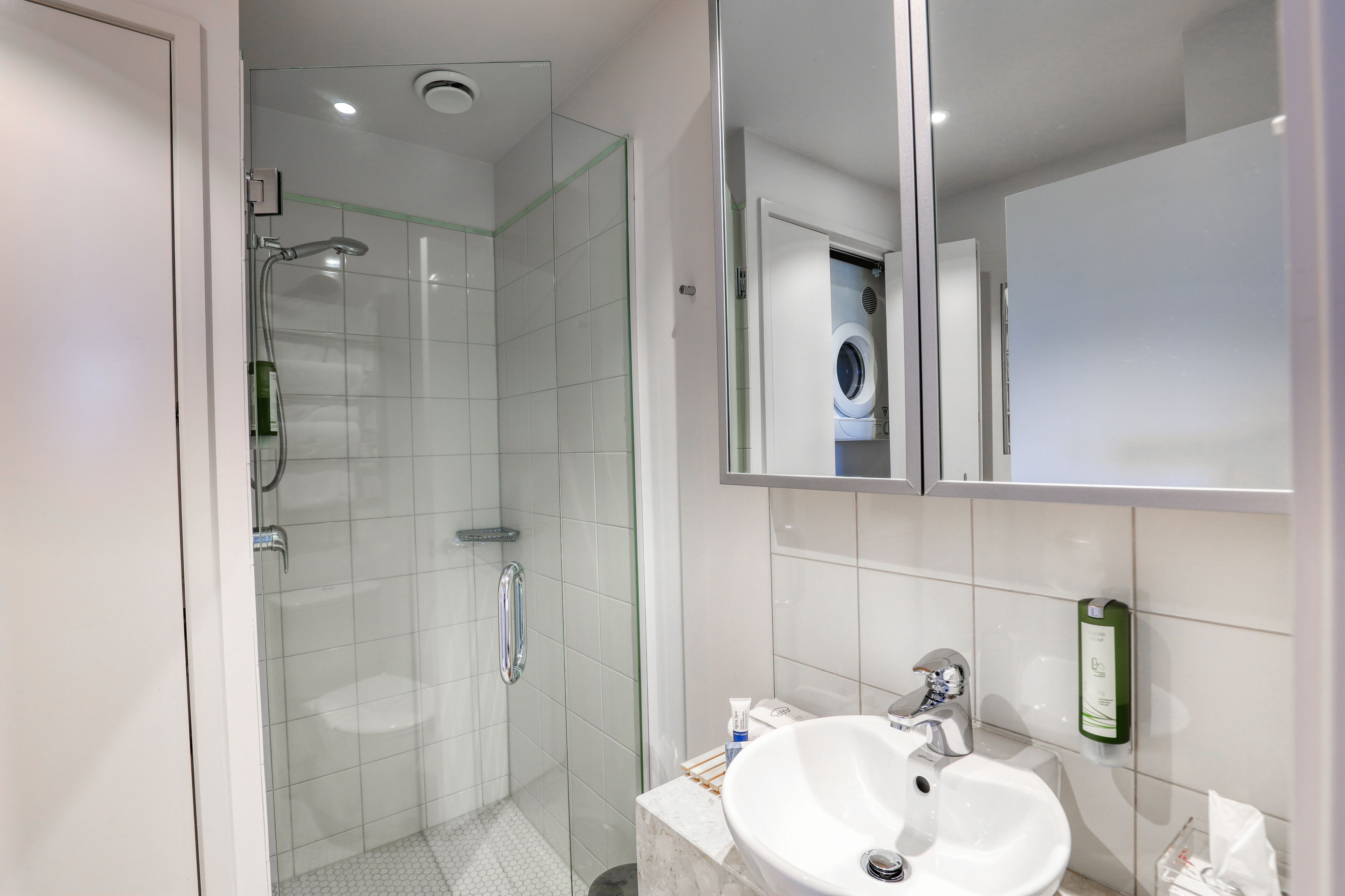 A modern bathroom with a glass-enclosed shower, a white sink, and a mirror above the sink.