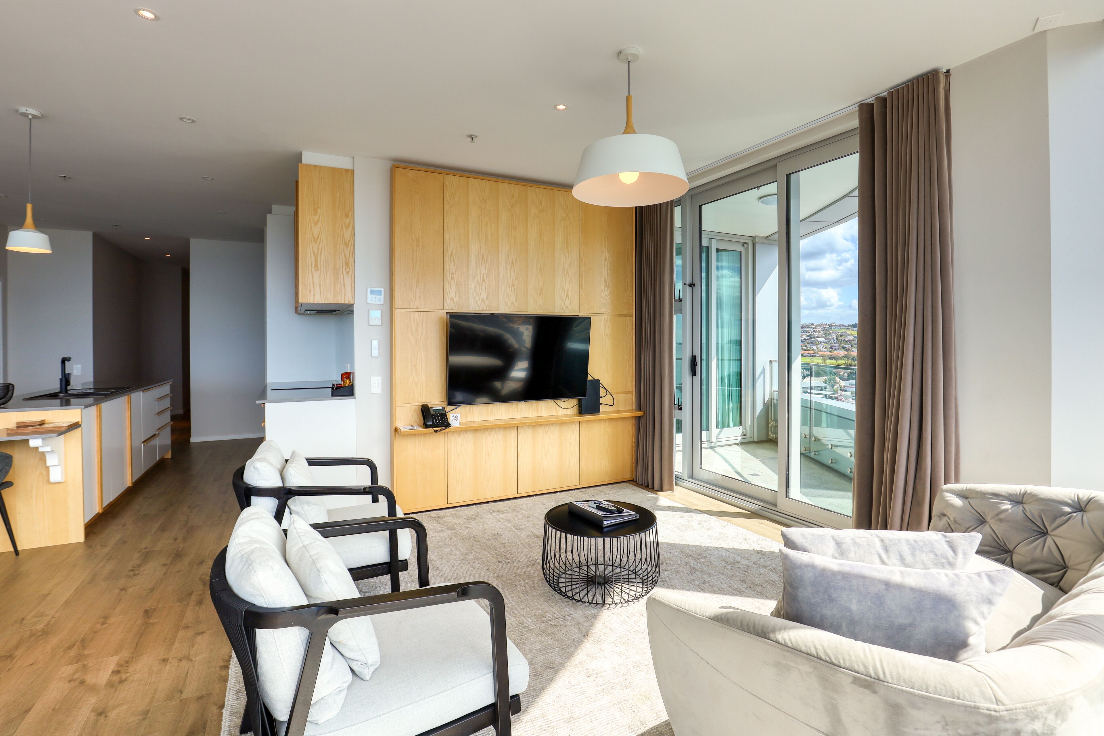 A modern living room with a sofa, chairs, a coffee table, and a TV mounted on a wooden wall.