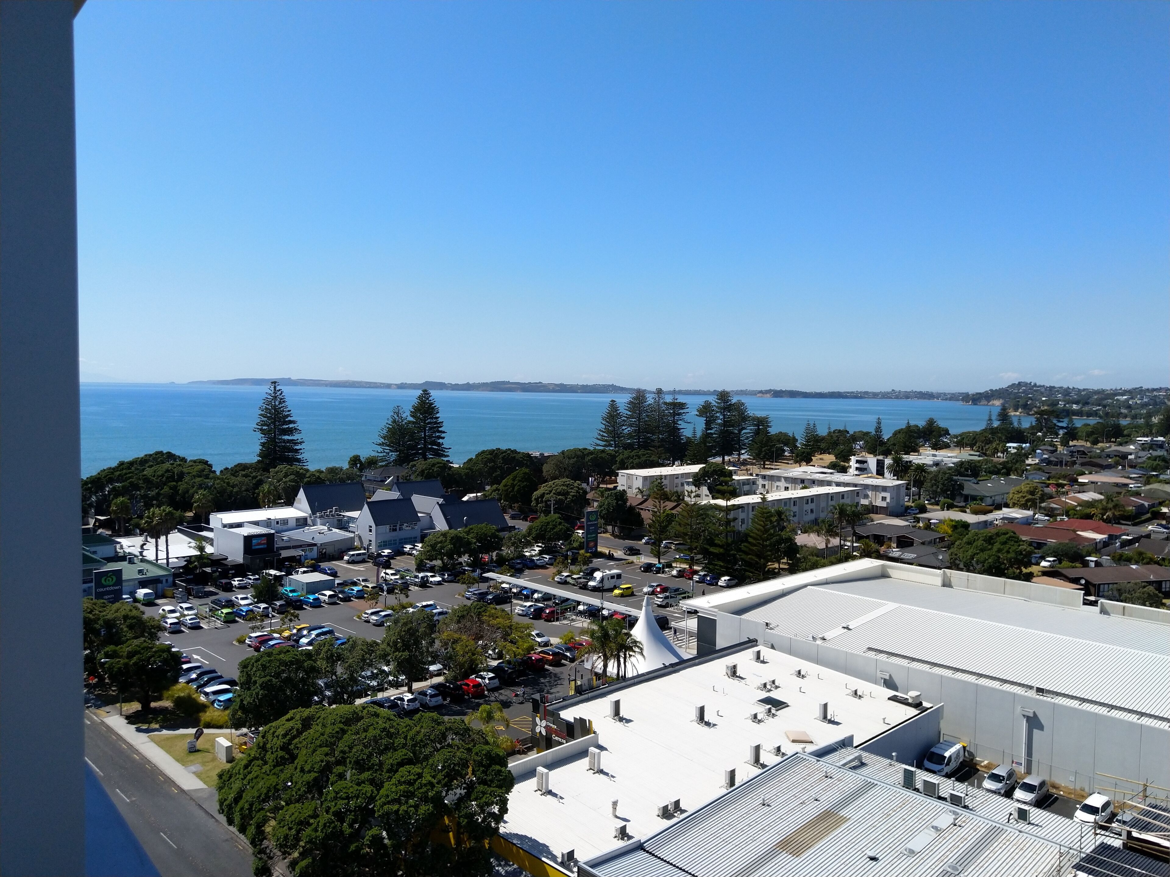 A coastal town with a marina, residential buildings, and a large white building with a curved roof.