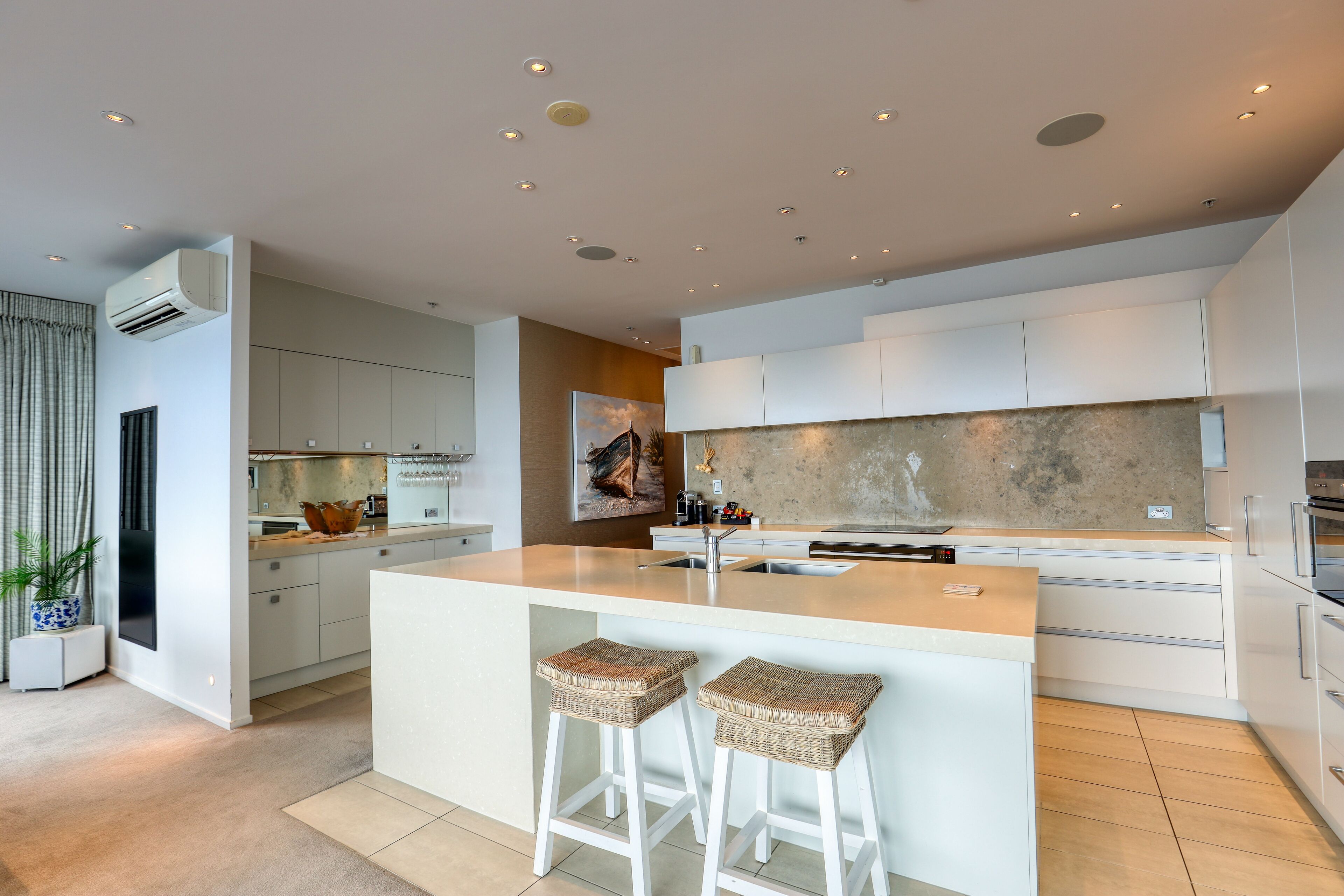 A modern kitchen with a central island, white cabinetry, and a large window.