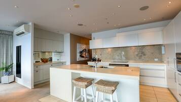 A modern kitchen with a central island, white cabinetry, and a large window.