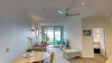 A modern living room with a dining area, a sofa, a TV, and a balcony with a view.