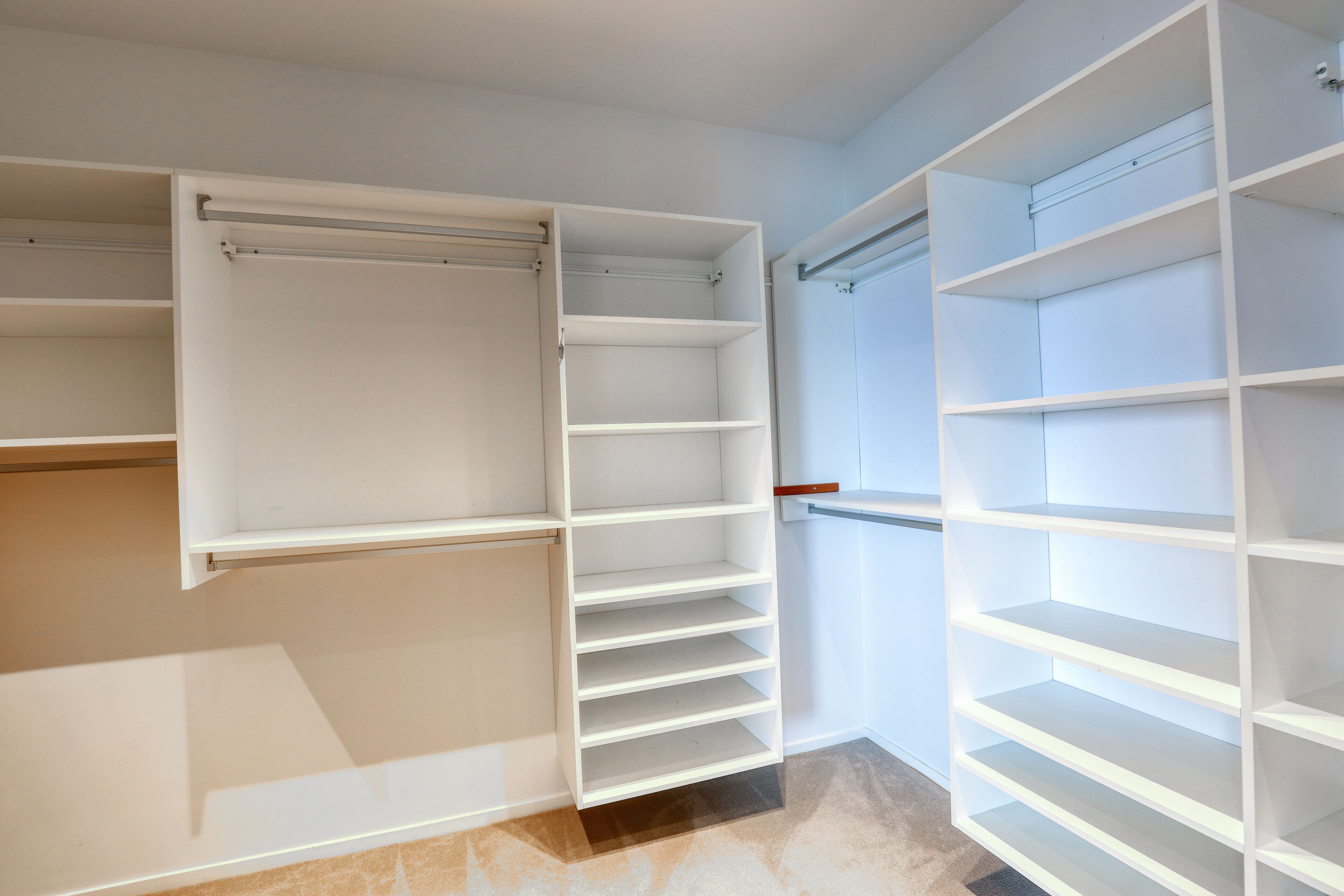 A room with a built-in closet featuring multiple shelves and hanging space.