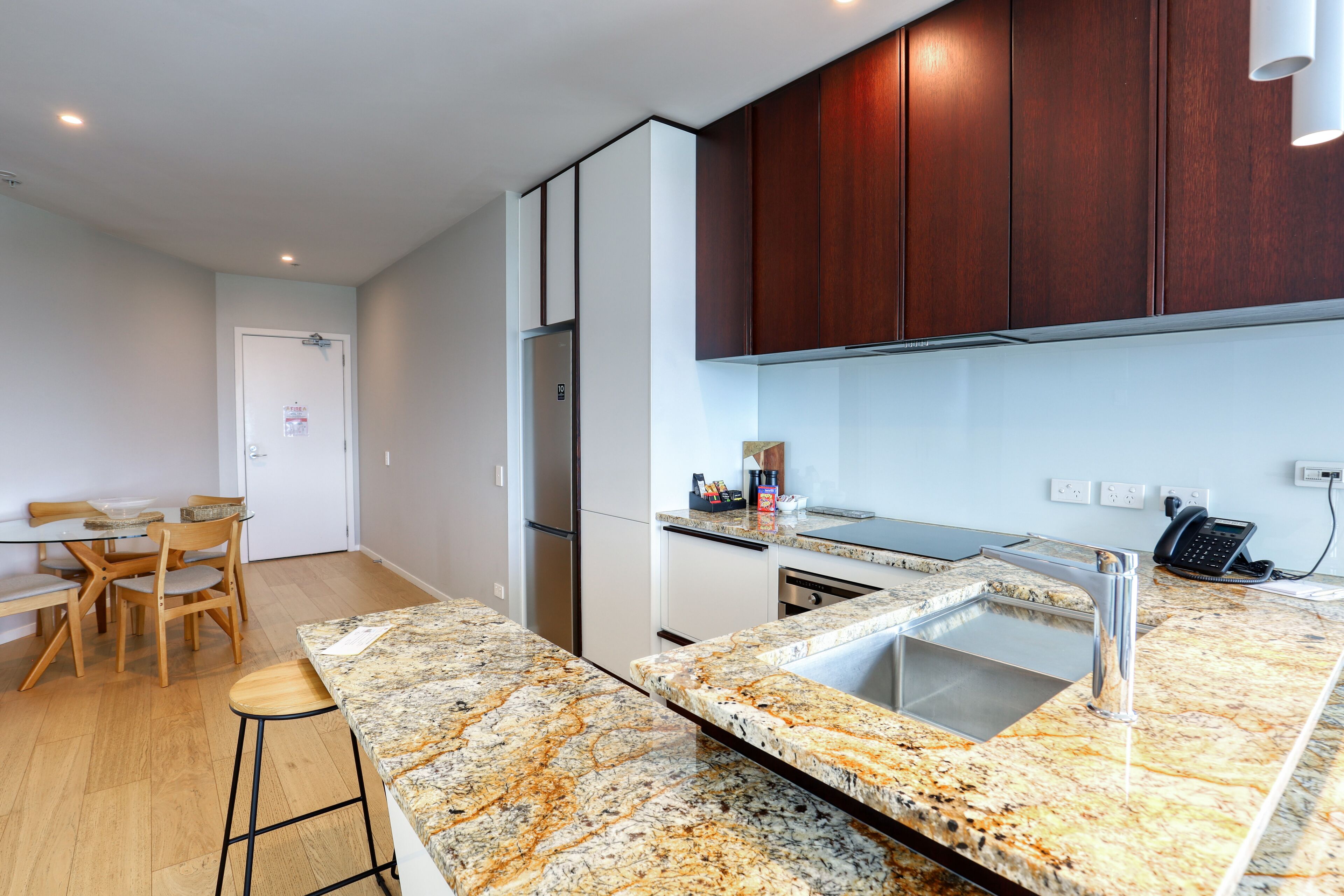 Una cocina moderna con encimera de granito, pileta de acero inoxidable y muebles de madera.