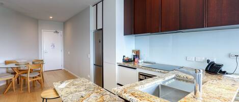 Una cocina moderna con encimera de granito, pileta de acero inoxidable y muebles de madera.