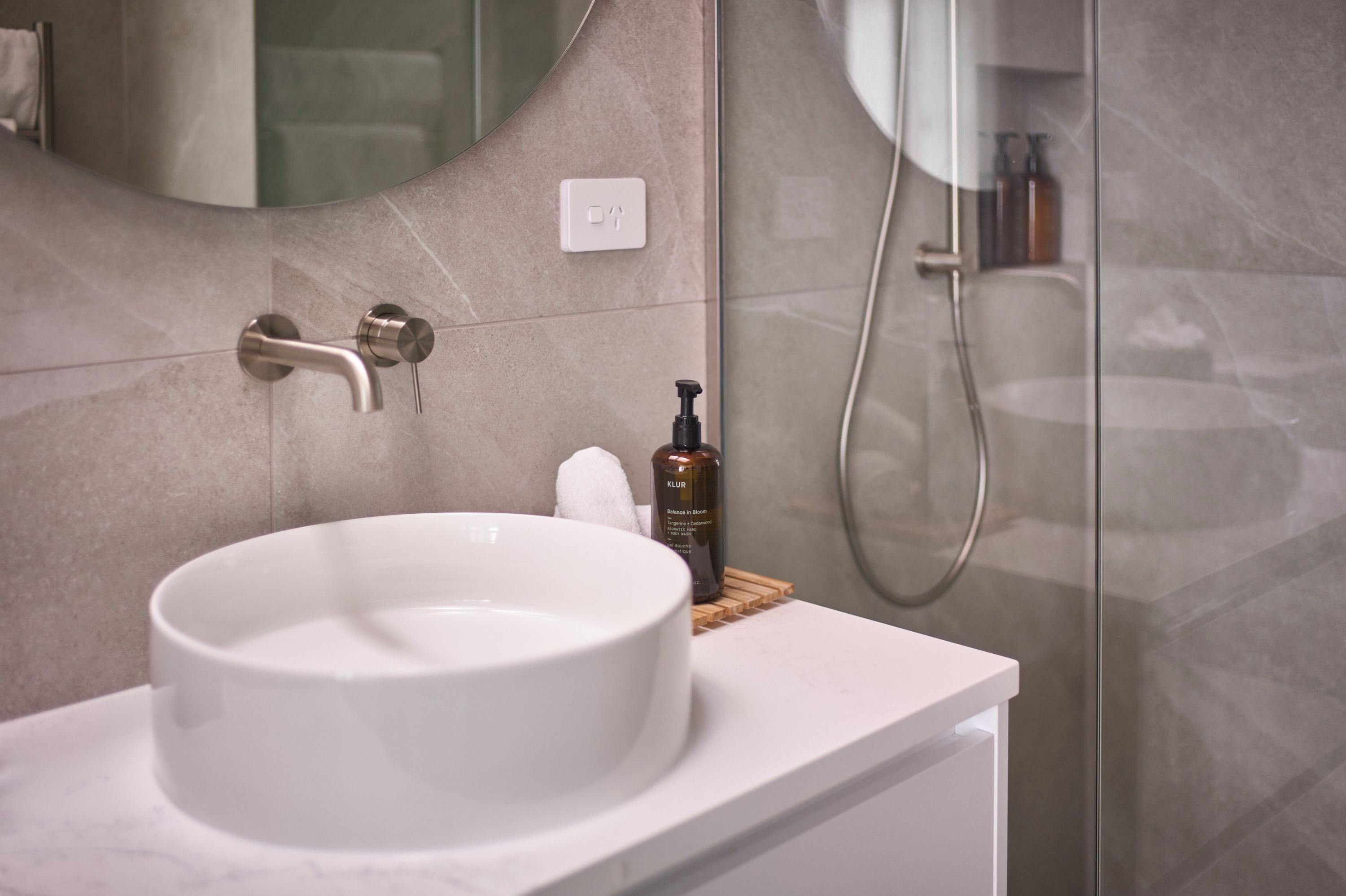 A bathroom with a white sink, a handheld showerhead, and a mirror.