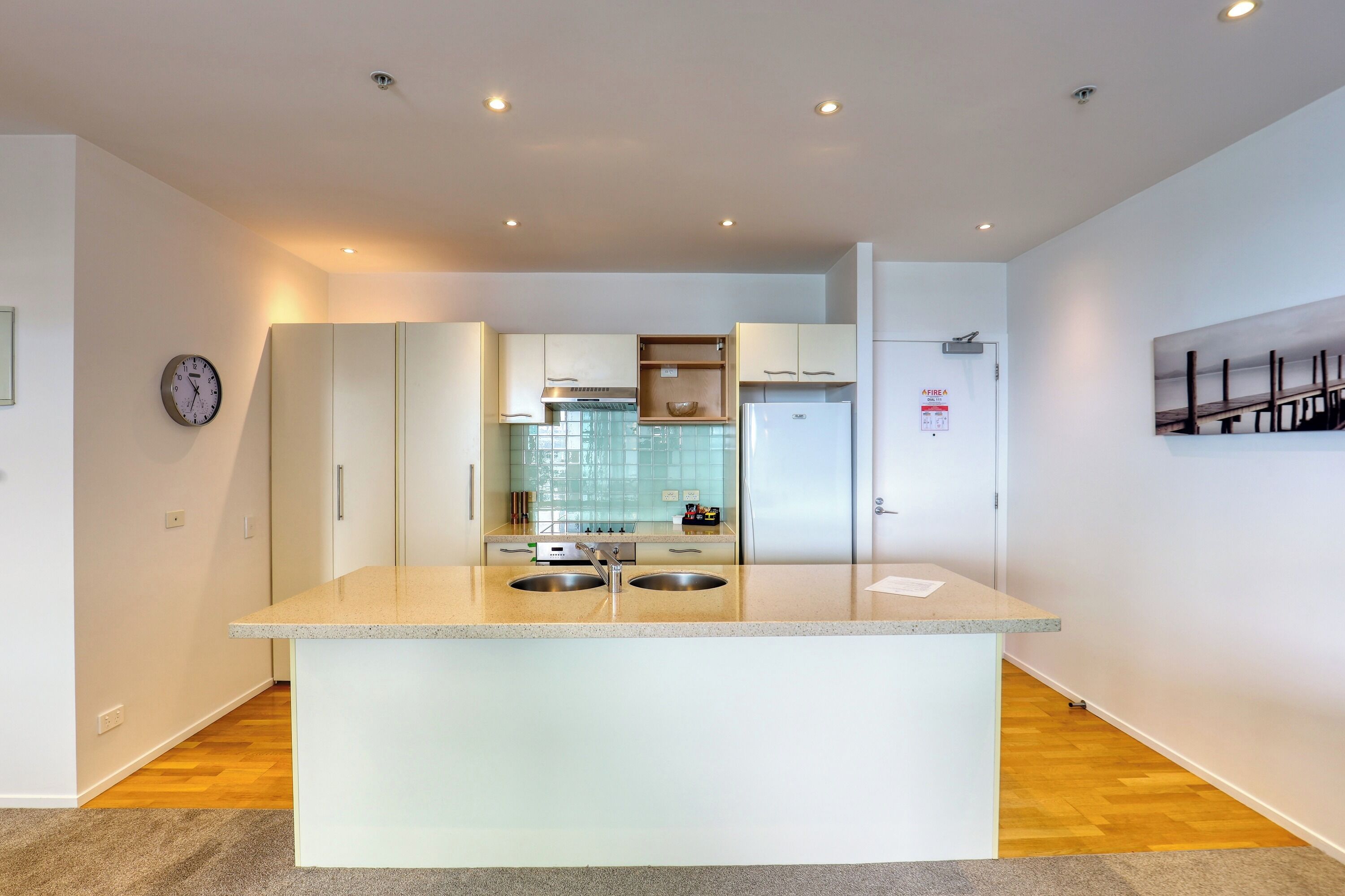 A modern kitchen with two sinks, white cabinets, and a stainless steel range hood.