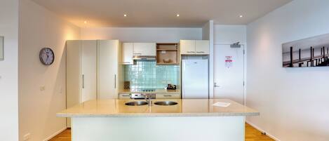A modern kitchen with two sinks, white cabinets, and a stainless steel range hood.