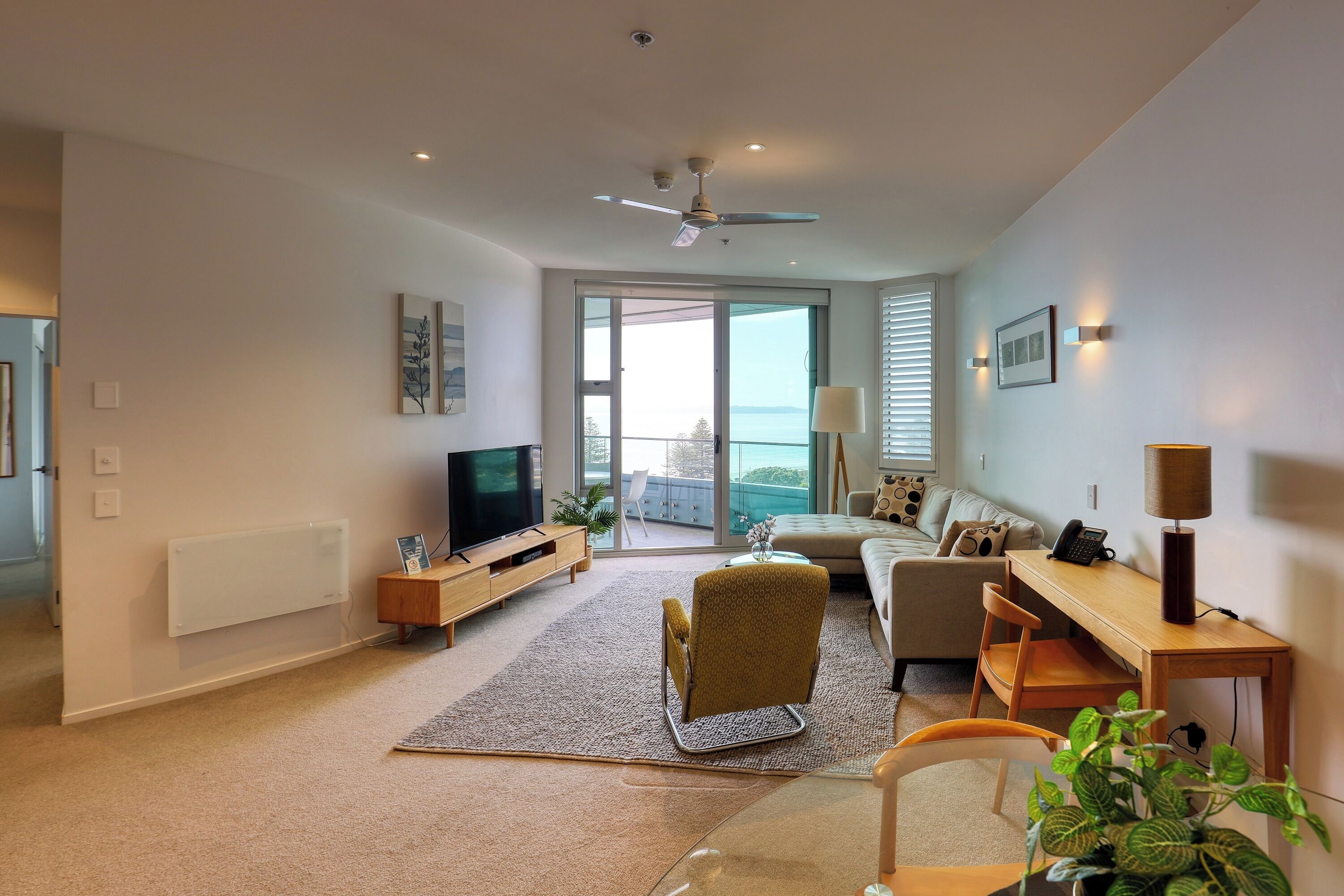 Una sala moderna con televisor de pantalla plana, un sofá, una mesa de centro y una zona de comedor con mesa y sillas de madera.