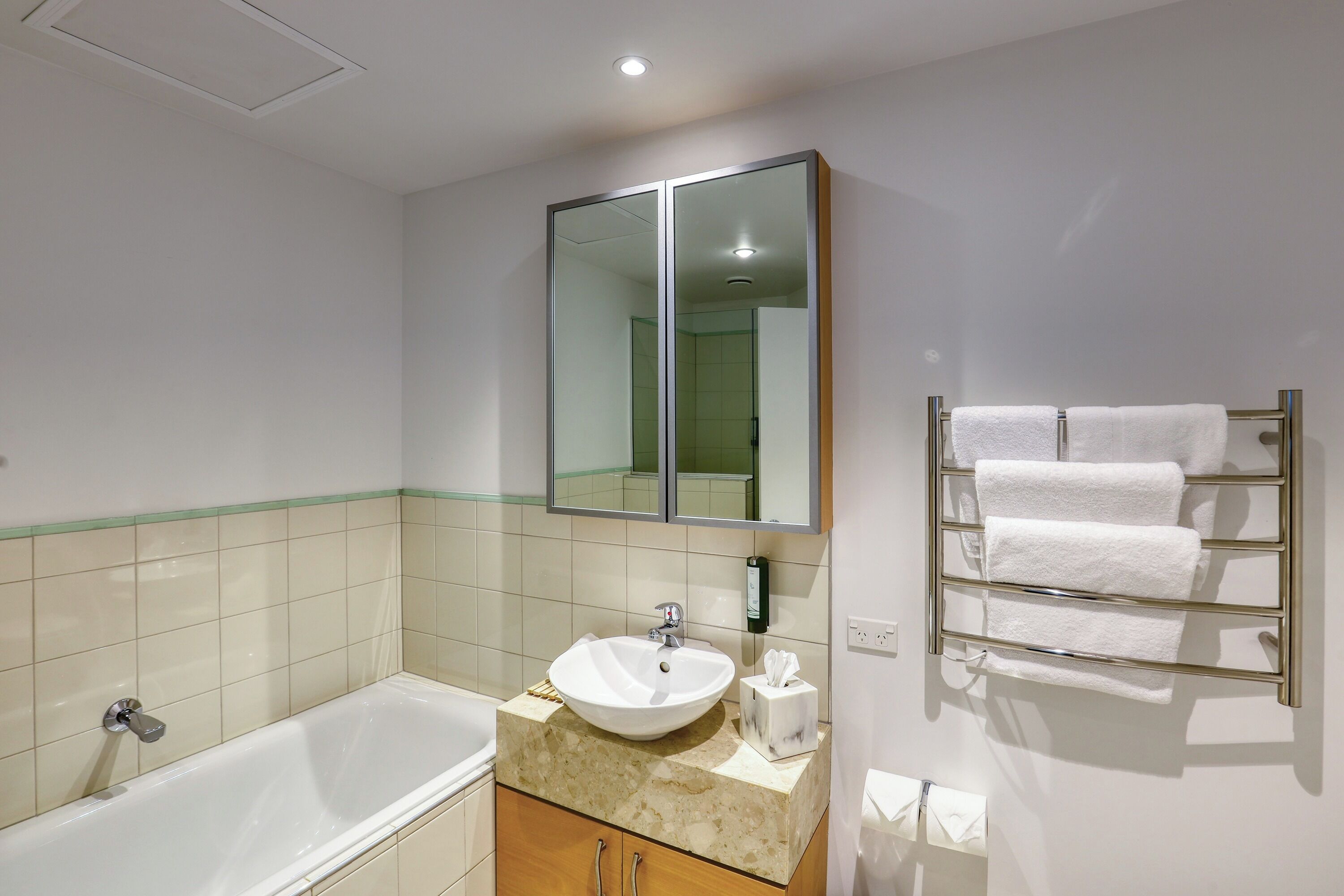 A modern bathroom with a bathtub, a sink, a mirror, and a towel rack.