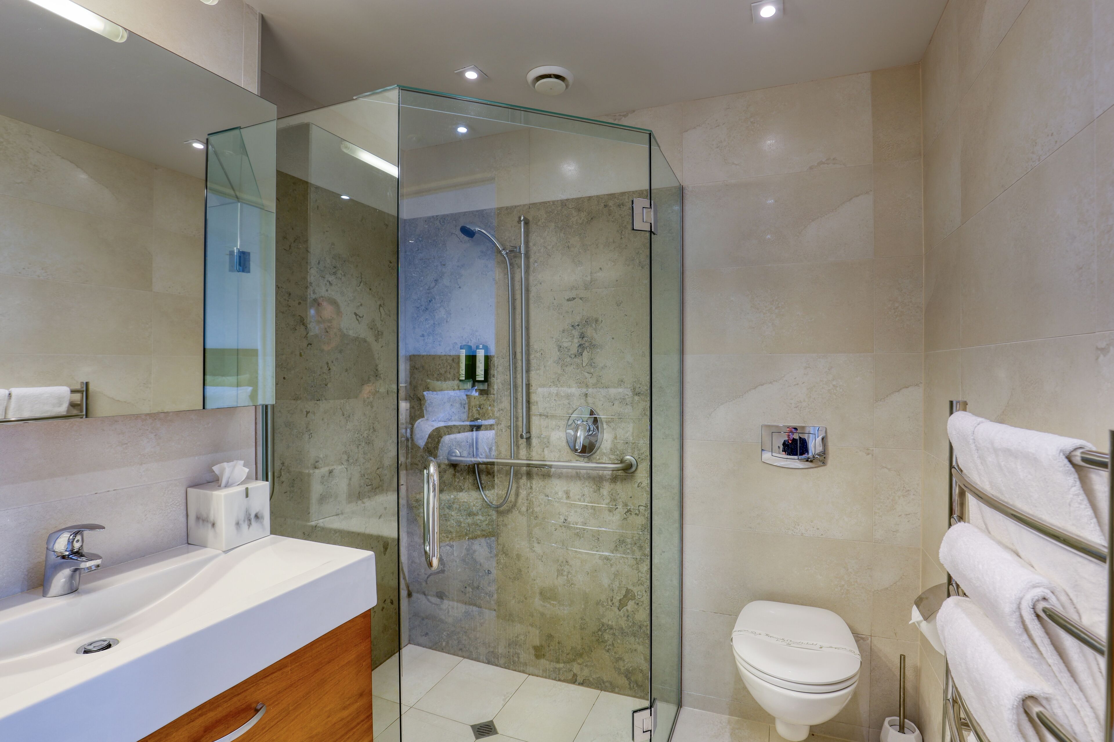 Une salle de bain moderne avec une douche à parois de verre, un lavabo blanc et des toilettes.
