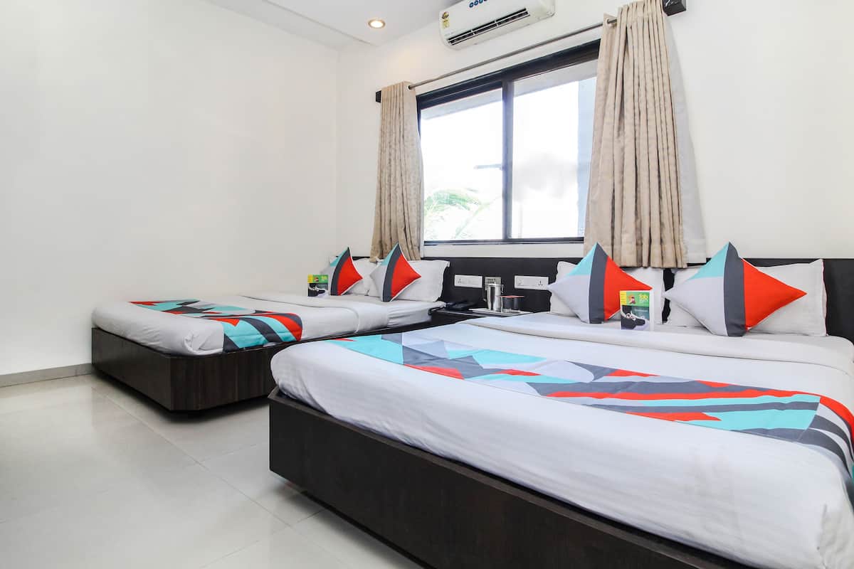 A hotel room with two beds, a nightstand, a window with curtains, and a ceiling fan.