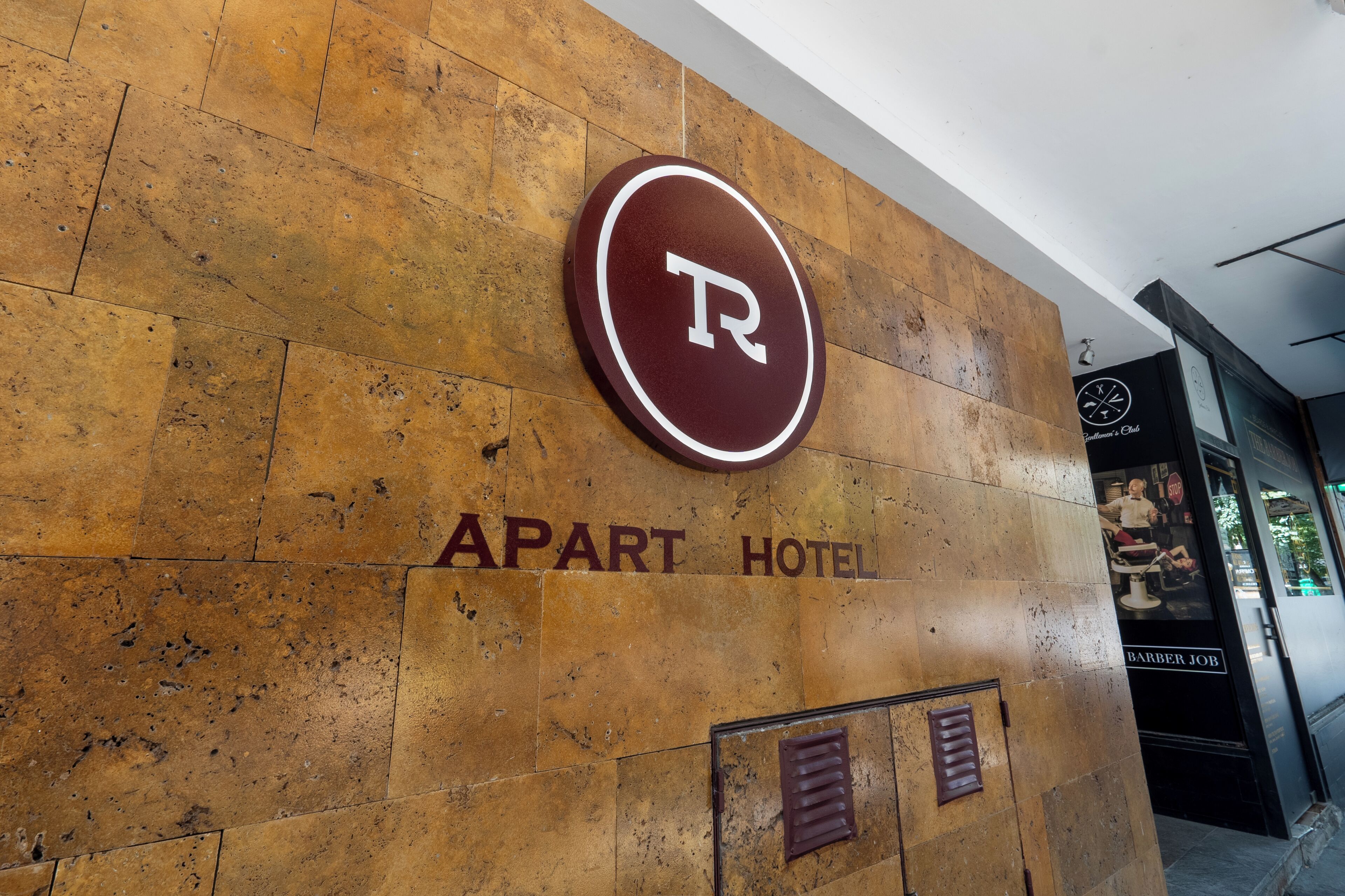Opaste, jossa lukee ”APART HOTEL”, ja jossa on pyöreä logo sekä selvästi näkyvä sisäänkäynti.