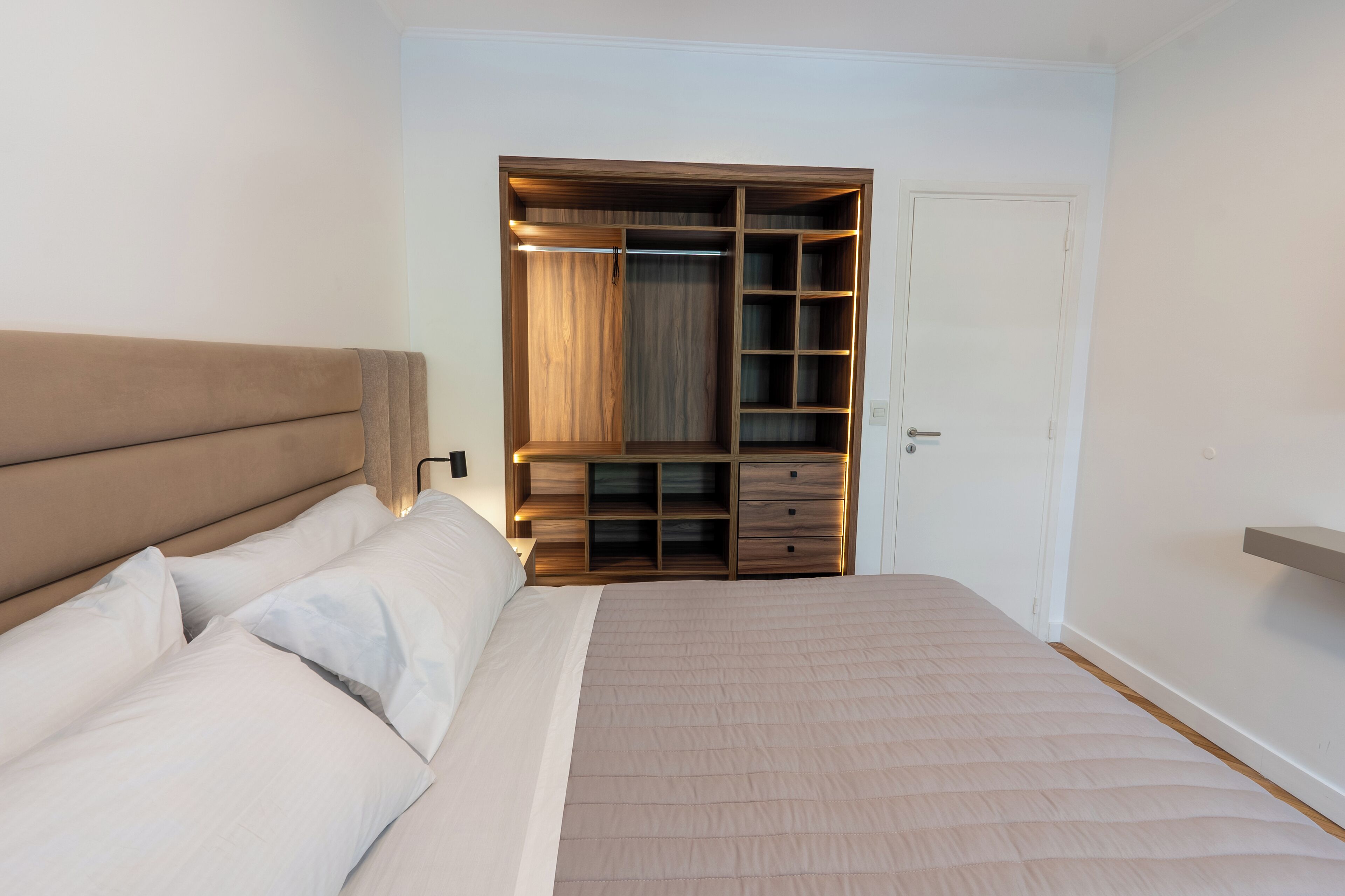 Un dormitorio con una cama, un armario de madera y una puerta.