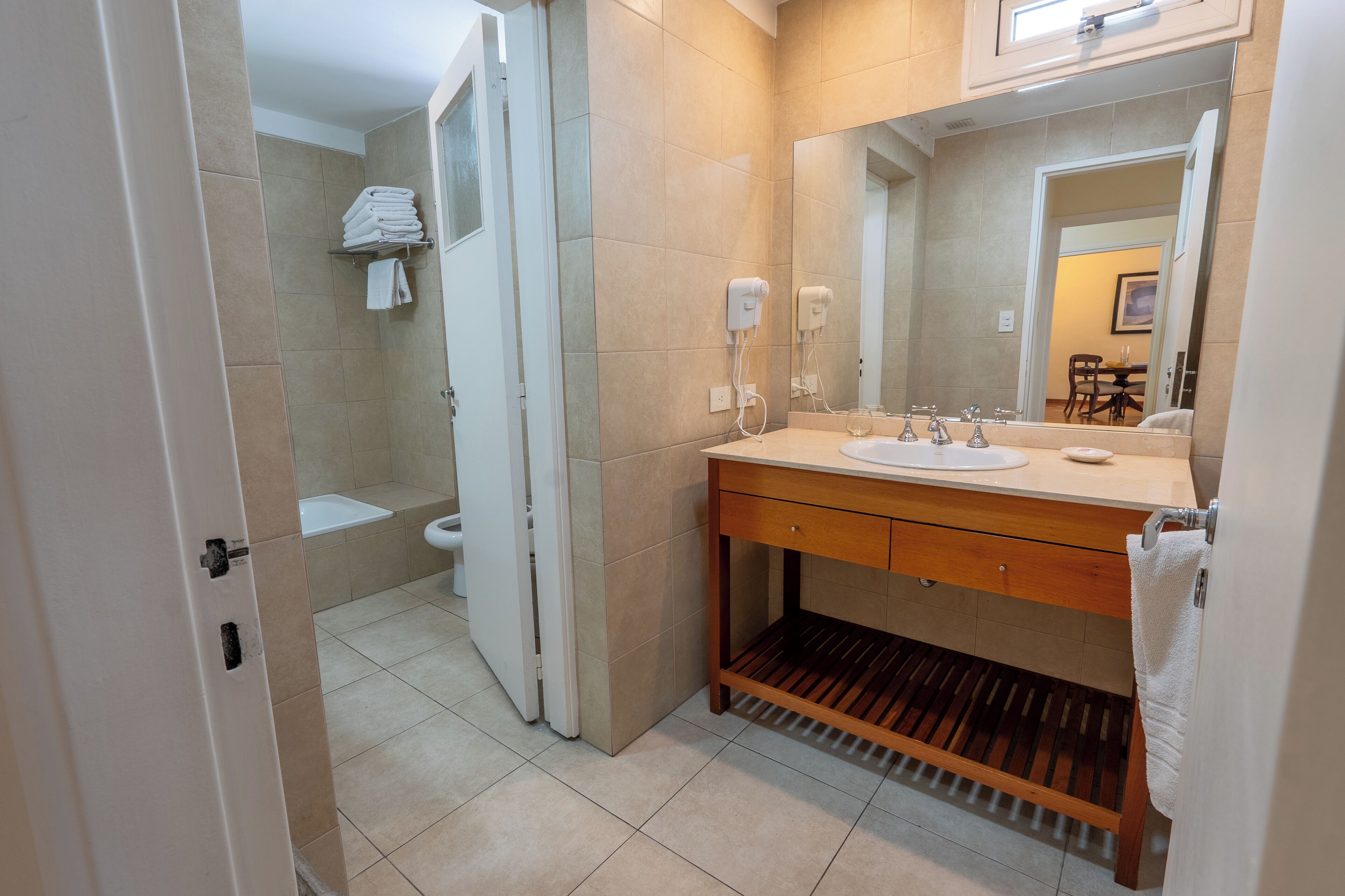 Un baño moderno con lavamanos, espejo y perchero para toallas.