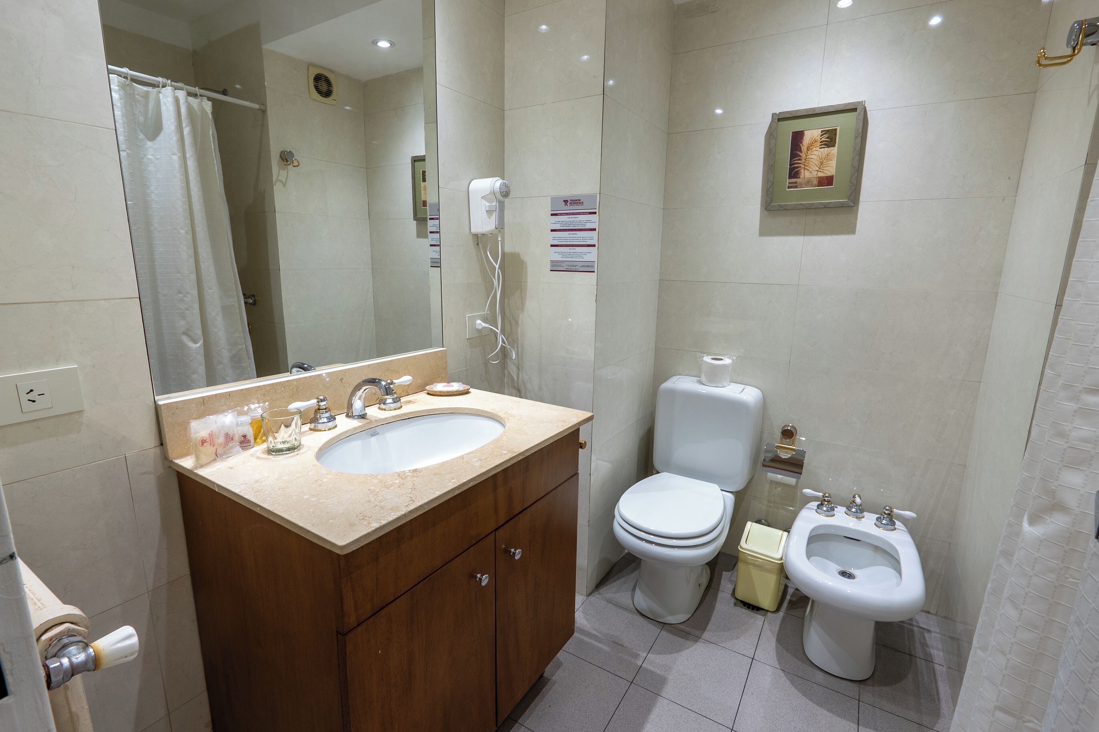 A modern bathroom with a double sink vanity, a toilet, a bidet, and a shower area.
