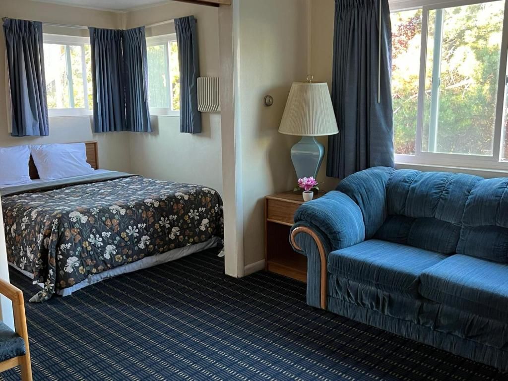 Een hotelkamer met een bed, een slaapbank, een nachtkastje met een lamp en een raam met gordijnen.
