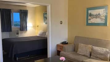 Hotellihuone, jossa on sänky, sohva, kukka maljakossa sohvapöydällä ja taulu seinällä.