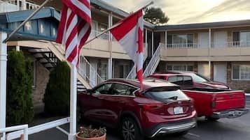 Ein Motel mit Parkplatz, zwei rote Autos und amerikanischen Flaggen.