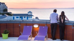 A couple overlooking a body of water with a view of a building in the background.