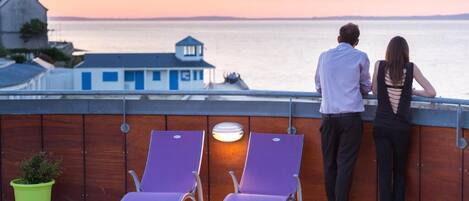 A couple overlooking a body of water with a view of a building in the background.