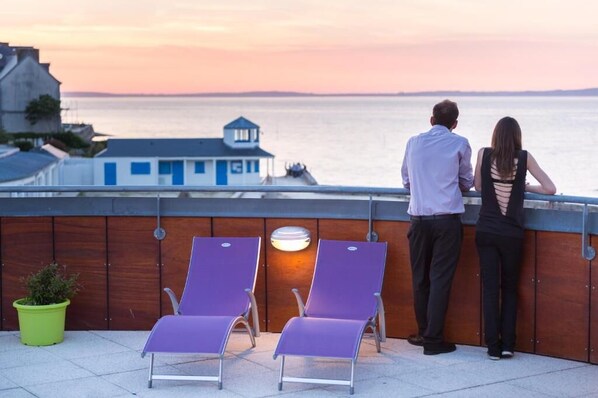 A couple overlooking a body of water with a view of a building in the background.
