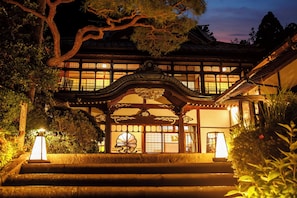 A traditional Japanese building with a wooden structure, a decorative entrance, and a staircase leading up to the entrance.