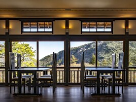 Comedor con mesas y sillas, ventanas amplias con vista a un paisaje montañoso.
