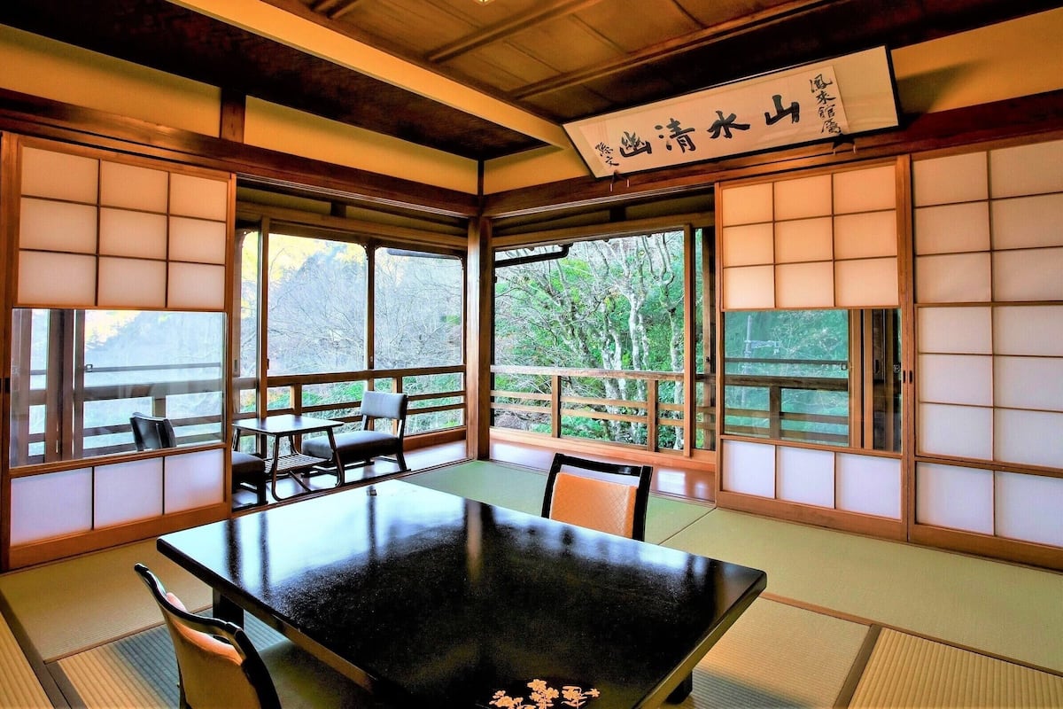 Una habitación japonesa tradicional con suelo de tatami, una mesa baja y puertas correderas.