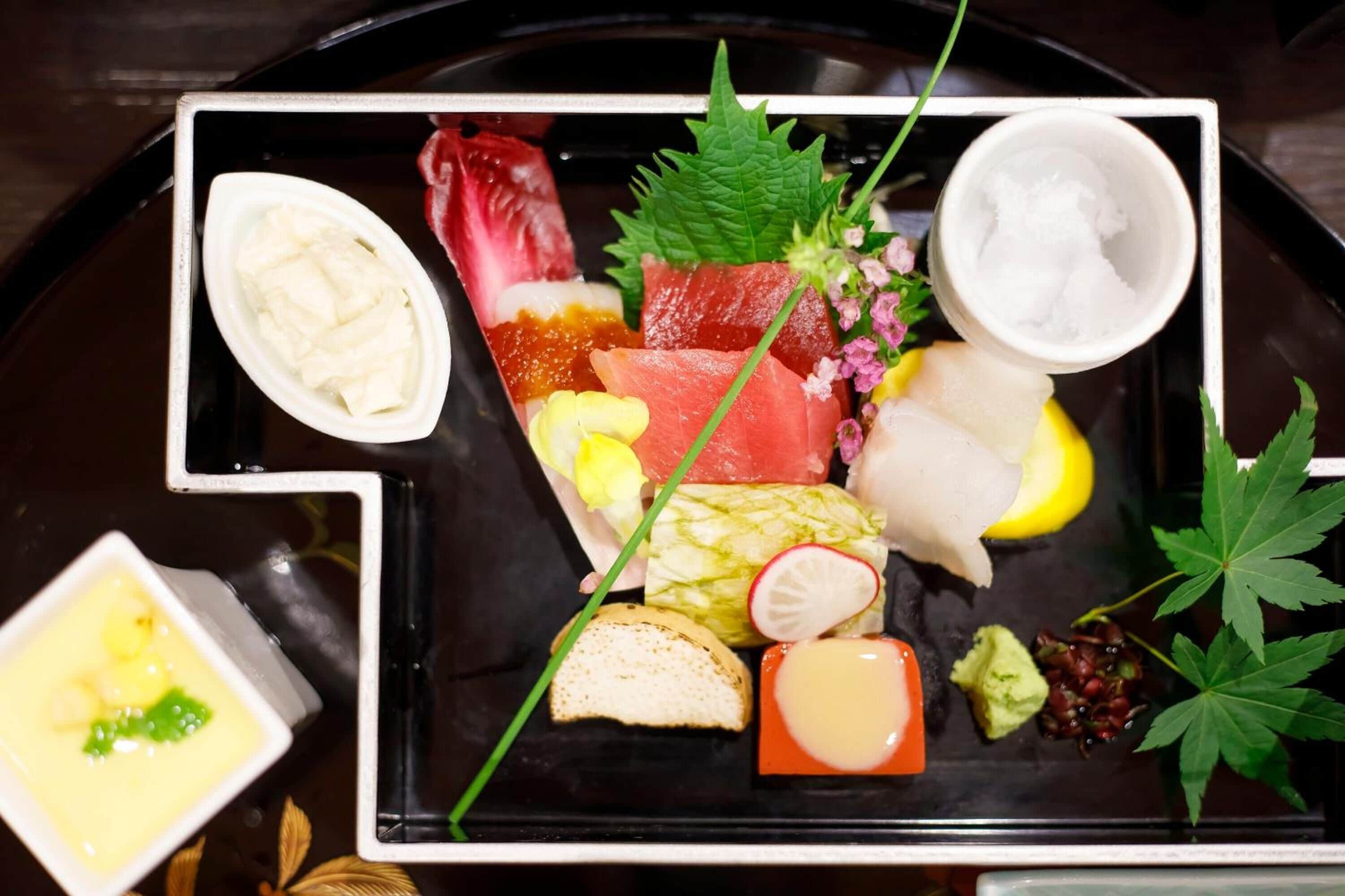 A tray with various food items including sashimi, pickled vegetables, and condiments.