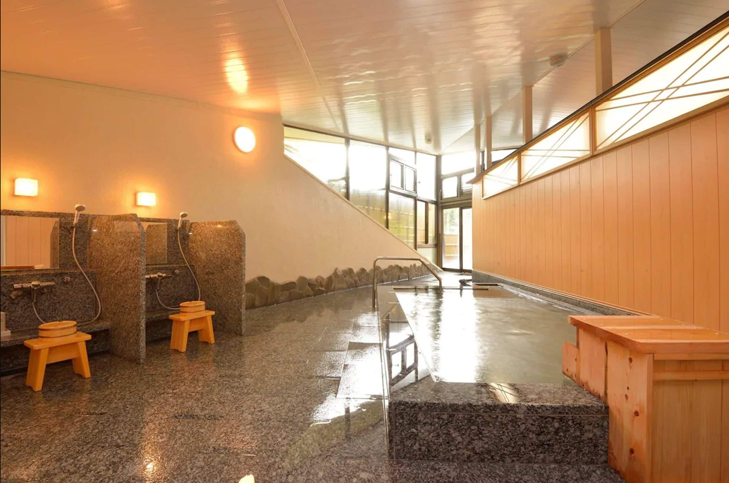 A modern indoor sauna with granite floors, wooden benches, and a glass ceiling.