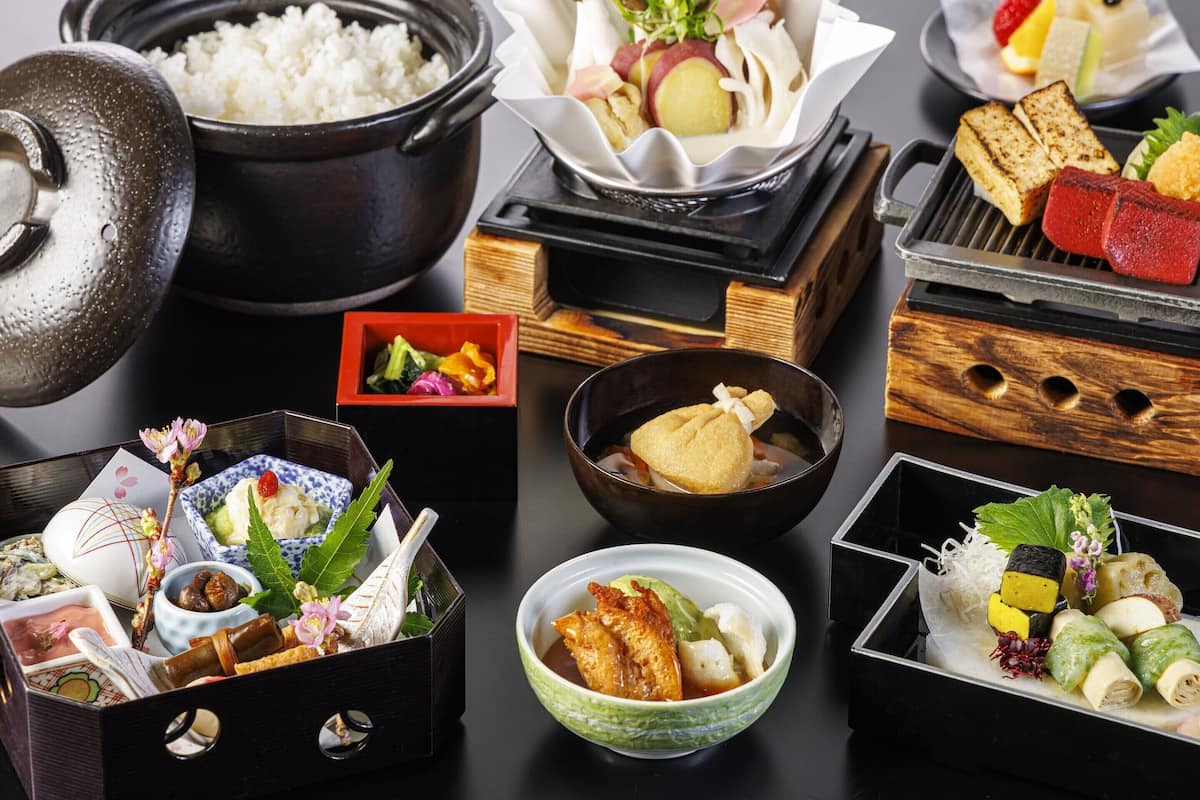 Variedad de platos japoneses, incluyendo arroz, tempura y carne a la parrilla, dispuestos sobre una mesa.