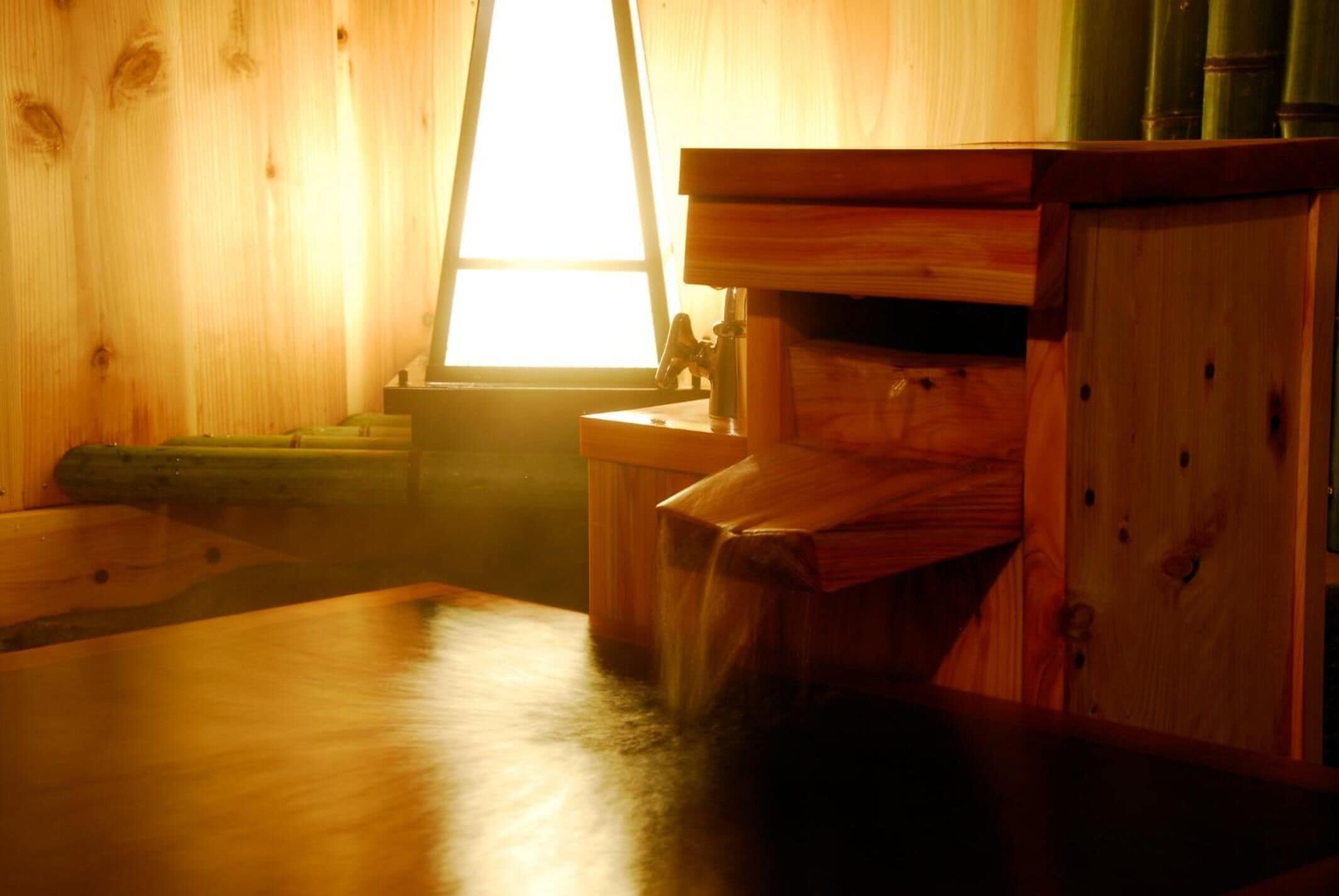 A wooden cabin interior with a window, a wooden table, and a cabinet.