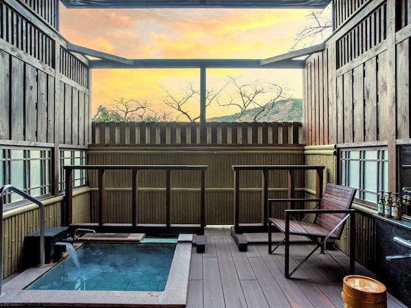 A wooden deck with a hot tub, seating, and a view of a sunset. - Hakone Kowakien Mikawaya Ryokan (Hakone)