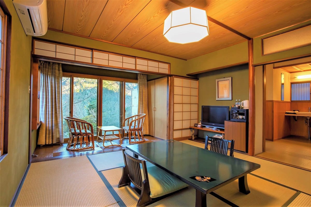 Una habitación tradicional japonesa con suelo de tatami, una mesa baja y un televisor.