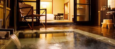 A traditional Japanese-style room with a hot spring bath, wooden furniture, and tatami mats.