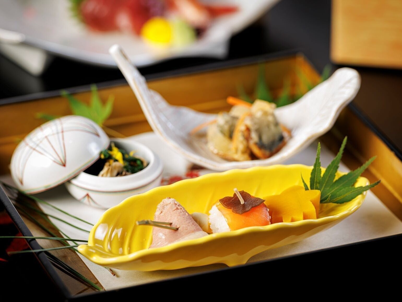 A tray with various dishes, including sushi and sashimi, on a wooden table.