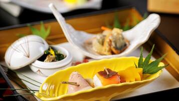 A tray with various dishes, including sushi and sashimi, on a wooden table.