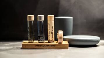 Four bottles of Pascal Morabito Paris hair products on a wooden stand with a plate and a cup in the background.
