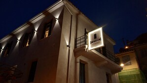 A building with a sign for 'Aethra Boutique Rooms' at night. - Aethra Rooms (Nafplio)
