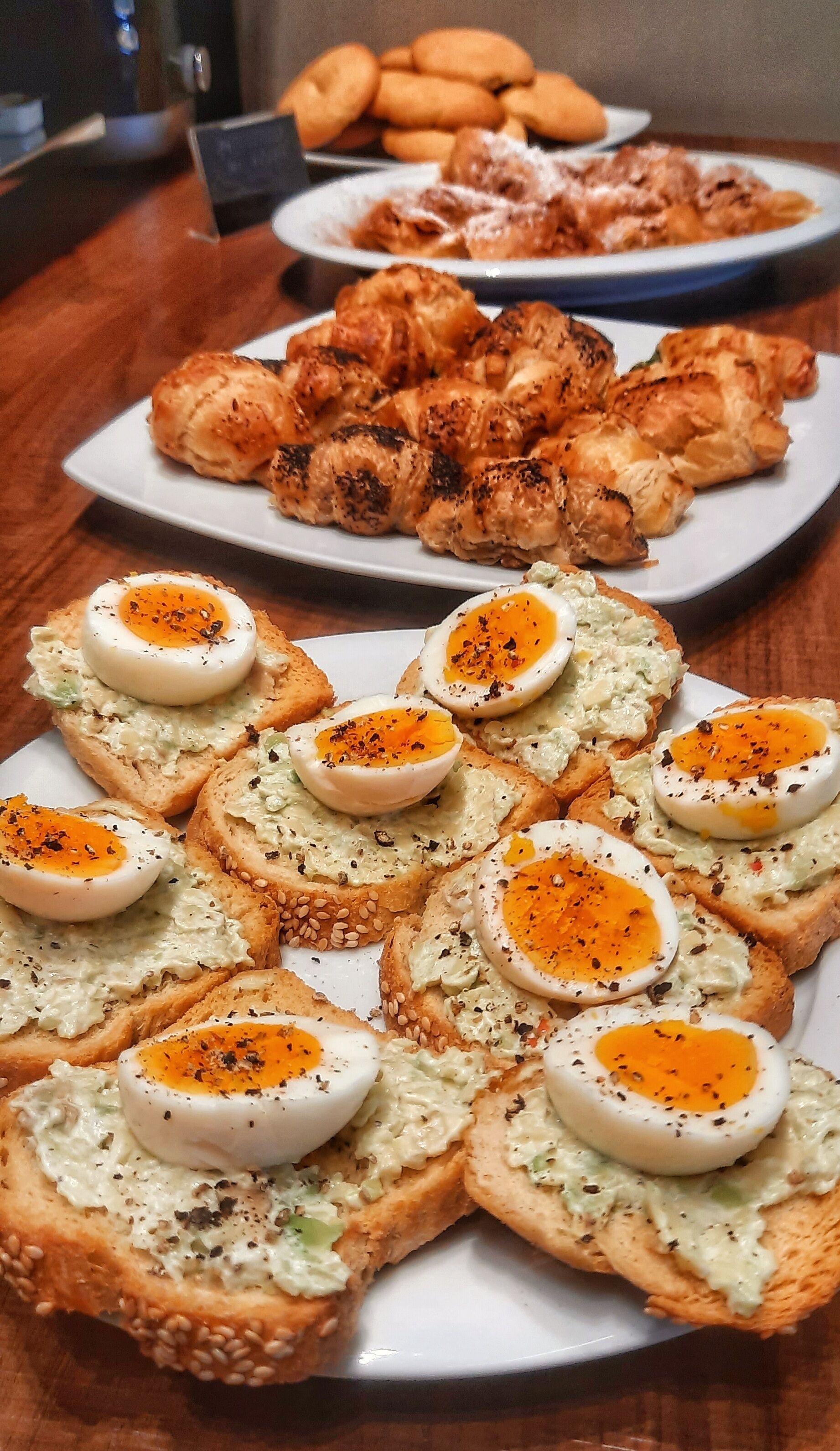 A table with various food items including bread with eggs and a plate of grilled chicken.