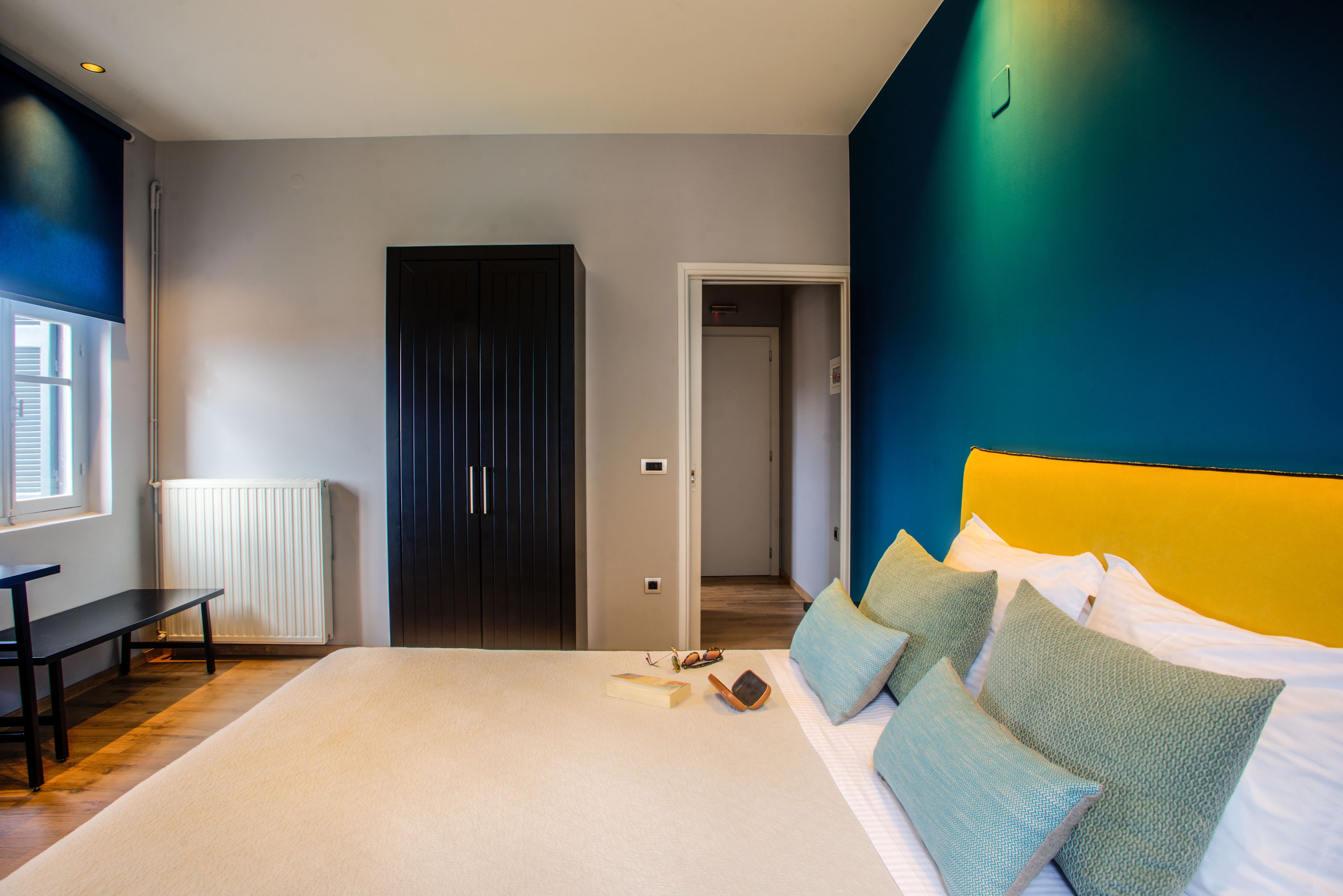 Une chambre à coucher avec un grand lit, un banc et une porte donnant sur une autre pièce.