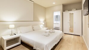 A neatly arranged bedroom with a bed, bedside tables, a wardrobe, and a television. - Ola Living Hostal Diagonal (Barcelona)