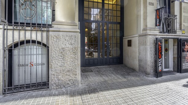A building entrance with a black door, a metal gate, and a sign for 'Frada's Design'. - Ola Living Hostal Diagonal (Barcelona)