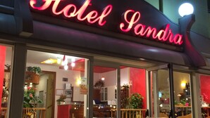 Entrada de hotel con un letrero de neón que dice "Hotel Sandra".