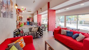 Un interior moderno con sofás rojos, un sofá estampado y un comedor con sillas y mesas.