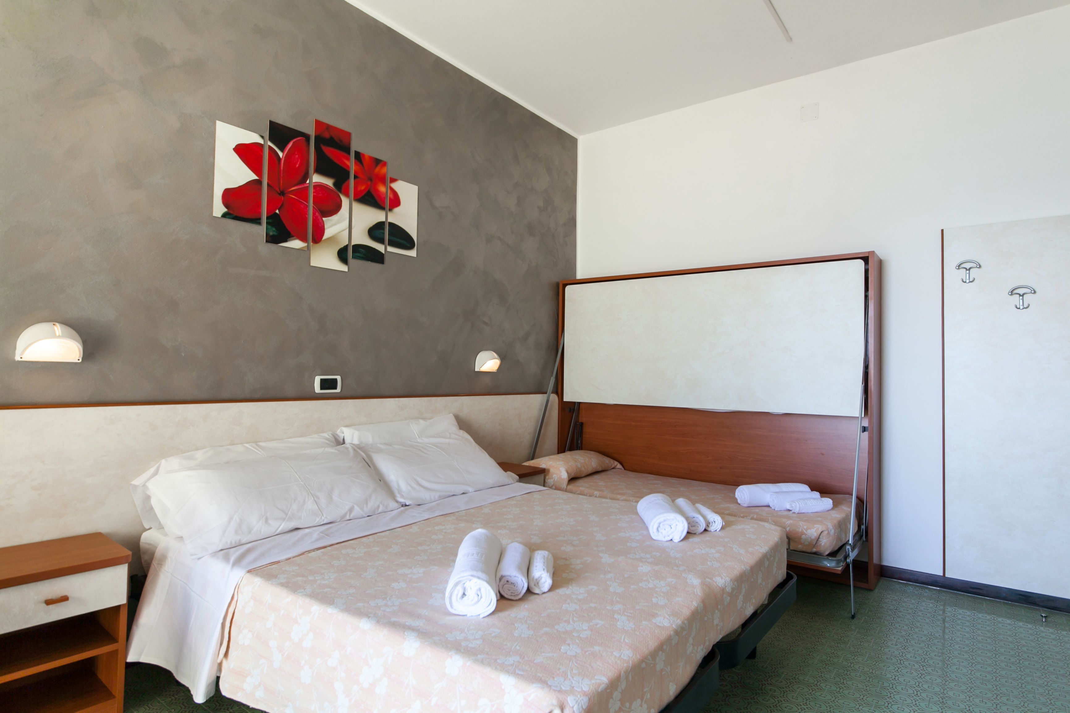 A hotel room with a large bed, two bedside tables, a wardrobe, and a wall-mounted artwork.